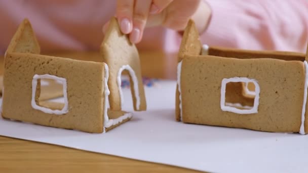 Womans hands make gingerbread houses glues details with sugar sweet icing. Cooking homemade gingerbread house. - Кадры, видео