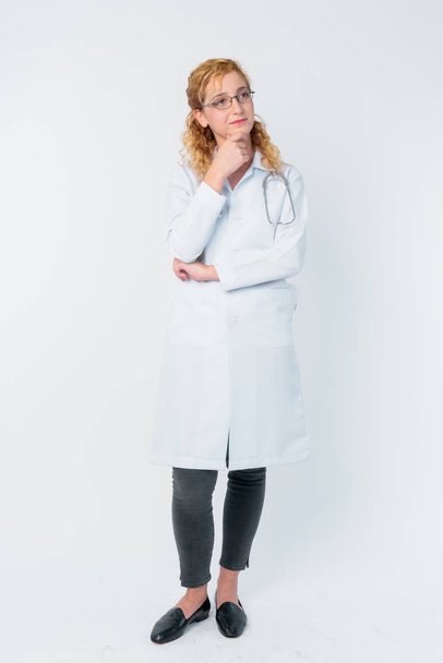 Full body shot of beautiful blonde woman doctor thinking and looking up - Foto, afbeelding