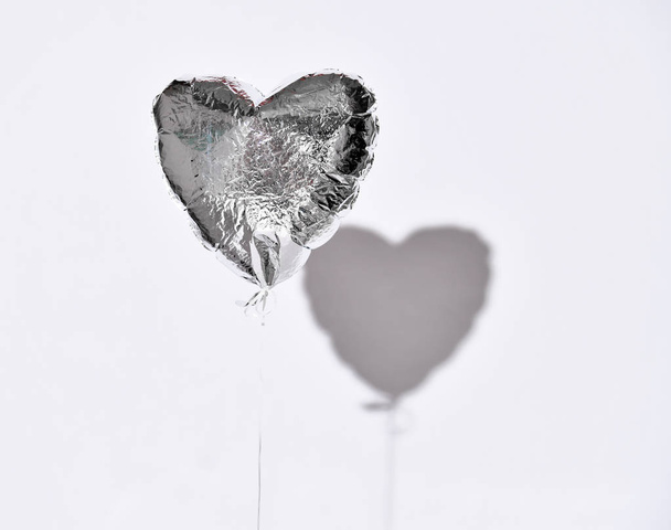 Party is over deflated silver heart balloon object  on white gray background with shadow - Φωτογραφία, εικόνα