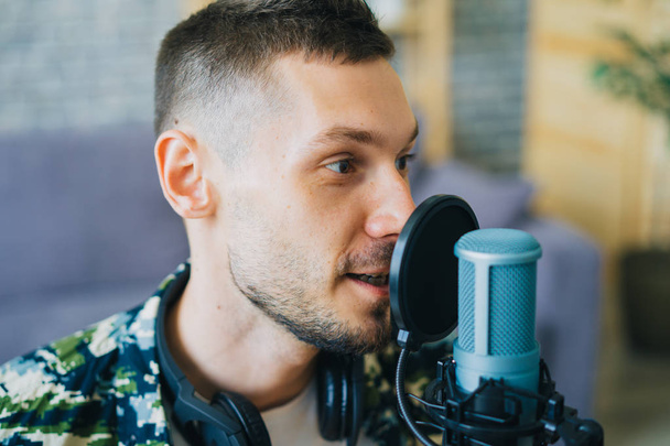 Крупный план мужчины-блогера, говорящего в подкасте микрофона в студии
 - Фото, изображение