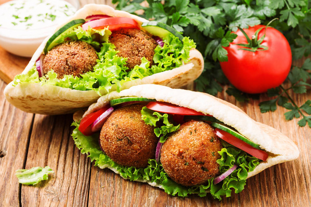 Falafel and fresh vegetables in pita bread on wooden table - Zdjęcie, obraz