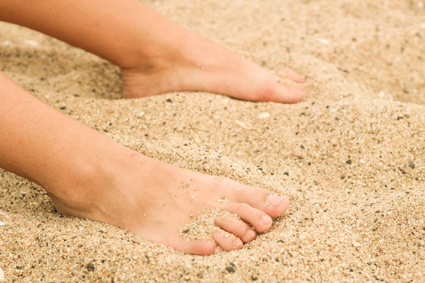 Vrouwelijke benen in het zand. Menselijke voet. Zee. Reclame - Foto, afbeelding