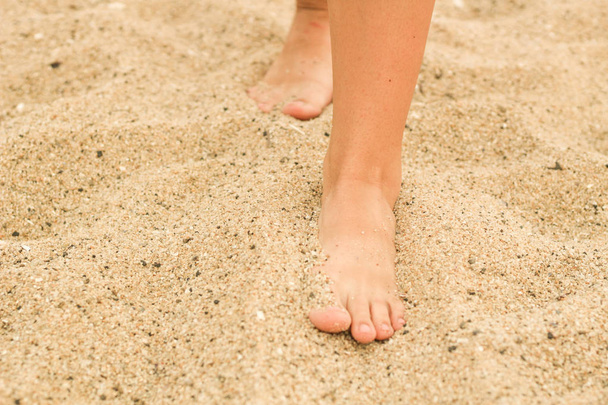 Patas femeninas en la arena. Pie humano. Mar. Publicidad
 - Foto, Imagen