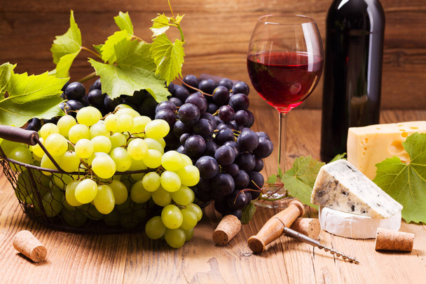 Glass of red wine, served with grapes and cheese  - Фото, изображение