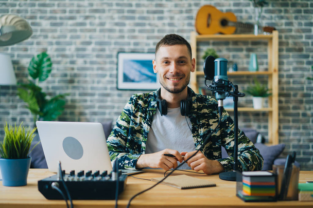 Portrait of young man blogger in recording studio near microphone smiling - Fotó, kép