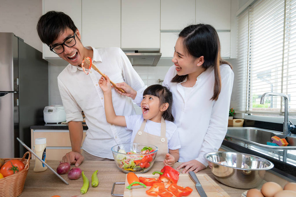 Filhas asiáticas alimentando salada para seu pai e sua mãe stand
 - Foto, Imagem