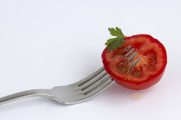 gesneden tomaat op voorvork op geïsoleerde witte achtergrond - Foto, afbeelding