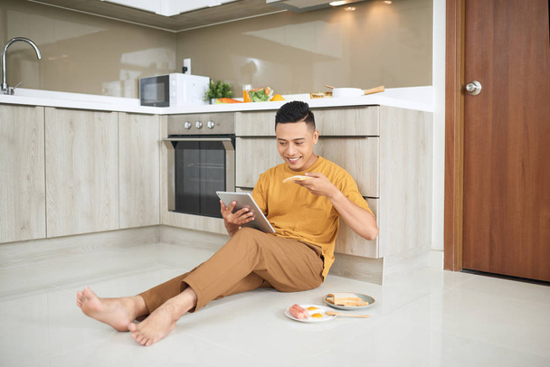 Aziatische jonge man werken thuis, een eigenaar van online business, eten - Foto, afbeelding