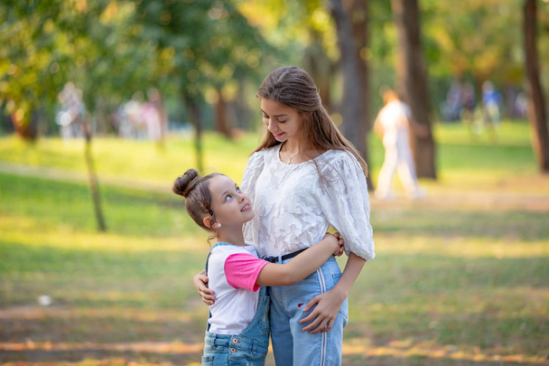Two sisters hug one another outdoors, happy family - Photo, Image