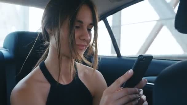 Portrait Young Woman using her Smartphone during Traveling in a Car with a Driver. Girl is checking Mails, Chats while she rides in a Taxi - Πλάνα, βίντεο