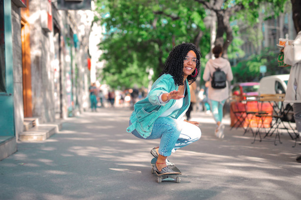 Curly girl on a skateboard - Zdjęcie, obraz
