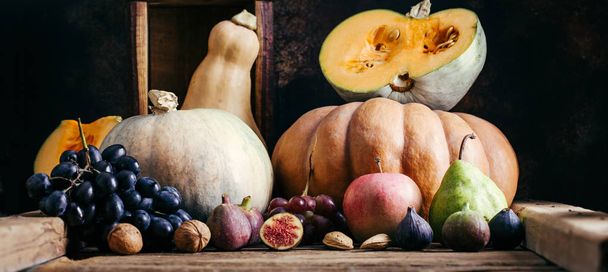 Autumn vegetables on a wooden background, pumpkin, grapes, figs, nuts - Foto, afbeelding