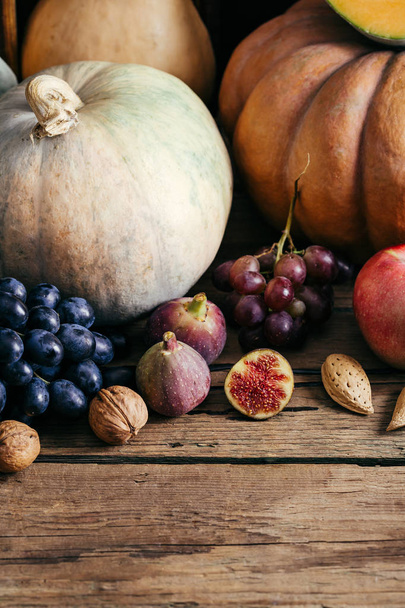 Autumn vegetables on a wooden background, pumpkin, grapes, figs, nuts - Foto, Imagem