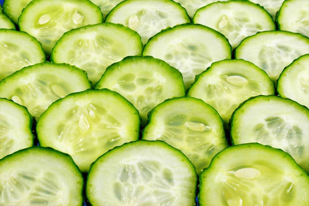 Komkommer-plantaardige achtergrond. Komkommers in het koken, toevoegen aan salades, soepen, snacks en sauzen, gezouten, ingeblikt, gepekeld. Komkommer cosmetica, verfrist en verjongt de huid.  - Foto, afbeelding