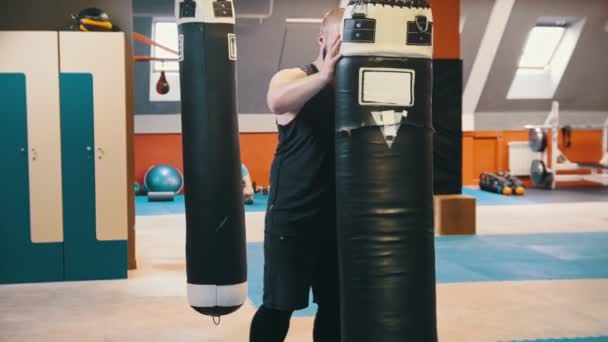Muž, který kulturista zvedne nahoru a nosí boxovací pytel na rameni v tělocvičně - Záběry, video