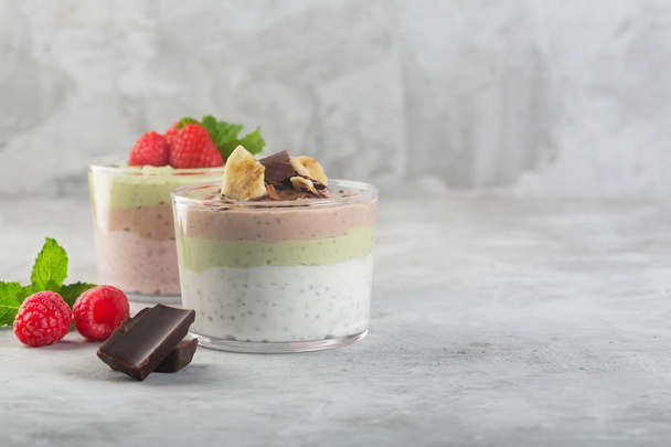 Chia seed pudding with three flavors, cocoa, matcha and strawberry with yoghurt, chocolate and mint leaves. Copy space - Фото, зображення