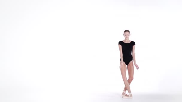 Professional ballerina dancing ballet on white cyclorama.Beautiful young girl with long hair wearing black suit isolated on white studio background.  - Footage, Video