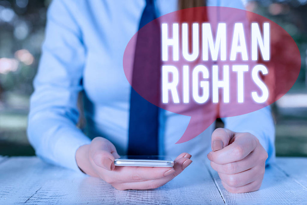 Writing note showing Huanalysis Rights. Business photo showcasing Moral Principles Standards Norms of a showing protected by Law Female business person sitting by table and holding mobile phone. - Photo, Image