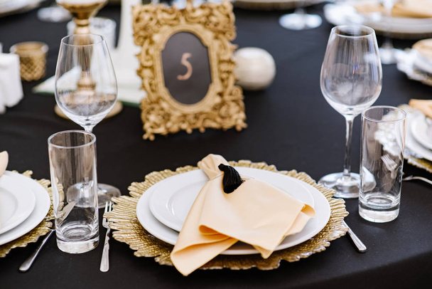 Fehér és arany lapok fekete abroszok. Esküvői asztalok és csodaszép szolgáltatások. - Fotó, kép