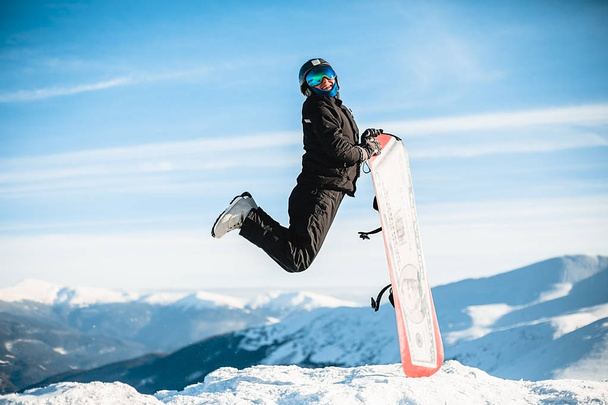 Happy man jumps with snowboard in mountains  - Foto, afbeelding