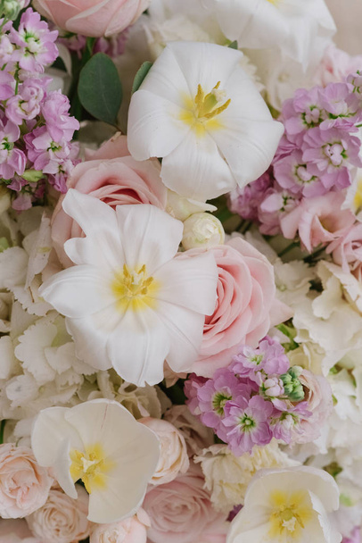 Незвичайні білі квіти, лілії з жовтими серединами серед інших квітів з флористичної композиції
. - Фото, зображення