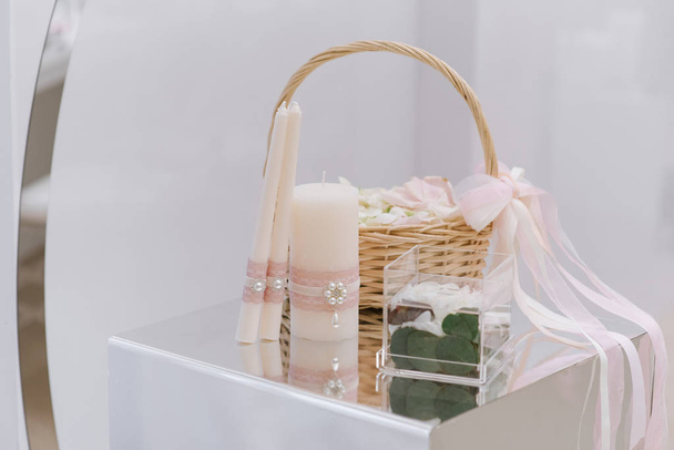 A fonott kosár természetes rózsaszirom, egy kis eljegyzési gyűrű doboz és esküvői gyertyák - Fotó, kép