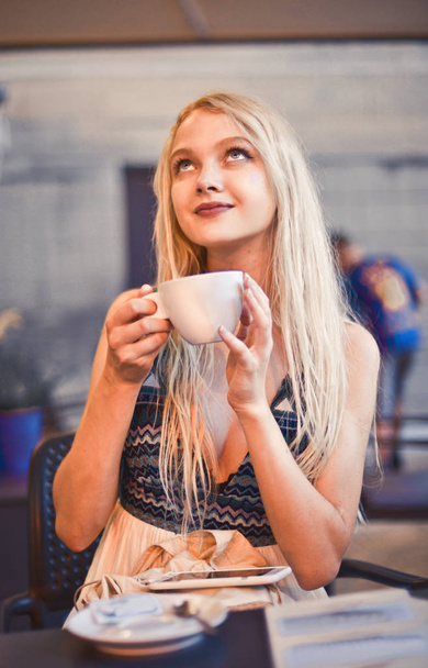 Blonde girl is drinking cappuccino in a bar - Φωτογραφία, εικόνα