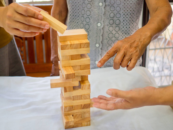 Uma mulher idosa está alegremente jogando um jogo de bloco de madeira com sua família na aposentadoria, Concept Risk management and strategy plan
 - Foto, Imagem