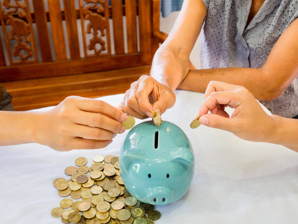 Vieille femme et deux filles mains mettent cions d'or dans la tirelire bleue, Économiser de l'argent pour le futur plan et le concept de fonds de retraite
 - Photo, image