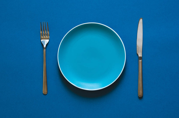 Color plate fork and knife isolated on blue background.  - Fotoğraf, Görsel