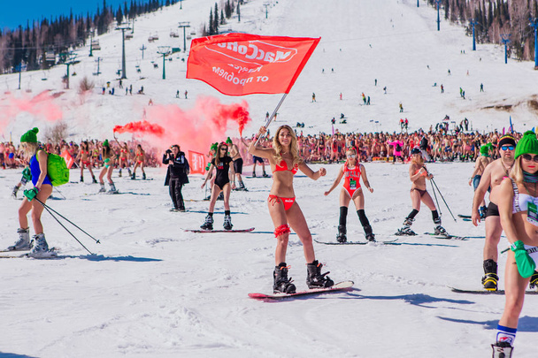 Sheregesh, Kemerovo region, Russia - April 13, 2019 : Crowd of people in bikini and shorts riding snowboard and mountain ski on the slope - Zdjęcie, obraz