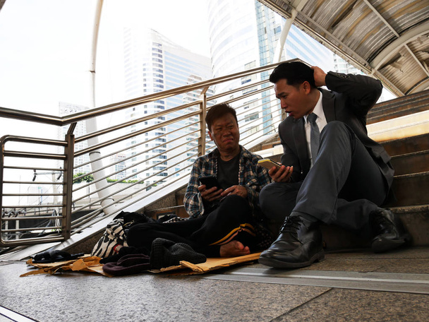 Крупним планом Бізнесмен і бездомний чоловік сидить на пішохідній вулиці
. - Фото, зображення