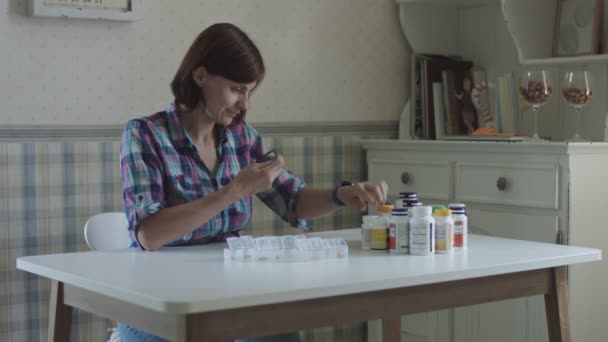 Young female sorting and taking vitamins sitting at table in provence interior. Women takes care of her health - Filmmaterial, Video