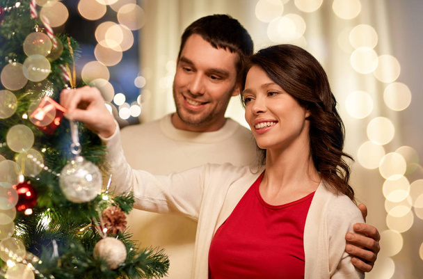 happy couple decorating christmas tree at home - Foto, immagini