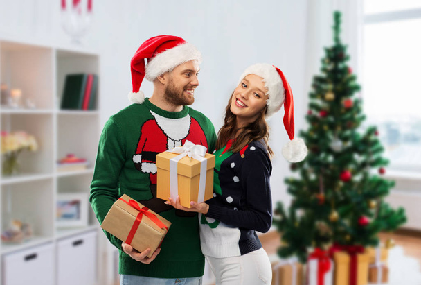 happy couple in ugly sweaters with christmas gifts - Foto, Imagem