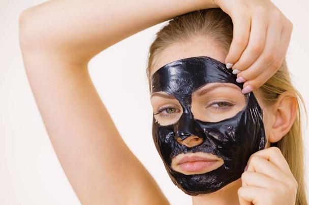 Girl removes black mask from face - Фото, изображение