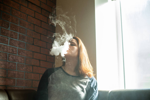 Vape nastolatek z problemem skóry. Portret młodej dziewczyny cute palenia elektroniczny papieros w barze. Zły nawyk, który jest szkodliwy dla zdrowia. Aktywność vaping. - Zdjęcie, obraz