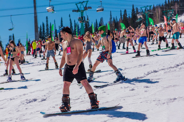 Sheregesh, Kemerovo region, Russia - April 13, 2019 : Crowd of people in bikini and shorts riding snowboard and mountain ski on the slope - Fotoğraf, Görsel