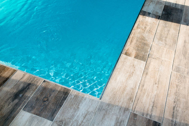 detalhe da piscina de canto ao ar livre com água azul
 - Foto, Imagem