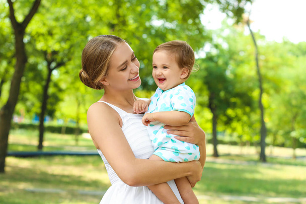 Beautiful mother with her cute baby in park on summer day - Photo, image