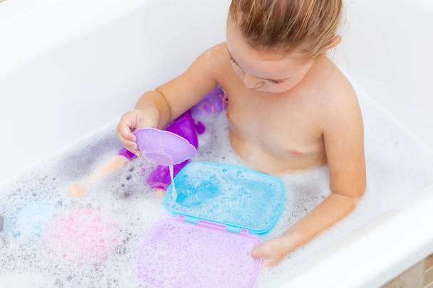 Femme tout-petit prend un bain et joue avec des jouets en plastique
 - Photo, image