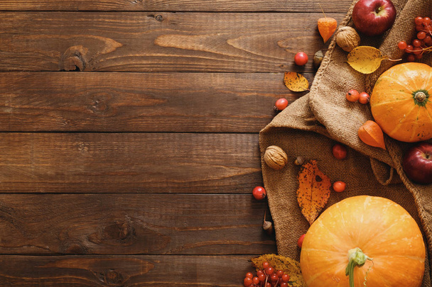 Oogst of Thanksgiving achtergrond met pompoenen, deken, gedroogde herfst bladeren, appels, rode bessen, walnoten op houten tafel. Platte lay compositie, bovenaanzicht, kopieer ruimte - Foto, afbeelding