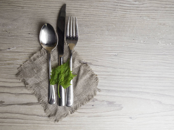 holiday table cutlery on wooden surface with green leaf - Foto, Bild