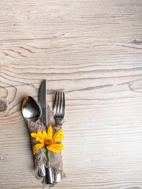 リネンナプキン、カトラリー、木製テーブルの上に黄色の下の素朴なテーブルの設定。休日のテーブルの装飾。ロマンチックなディナー. - 写真・画像
