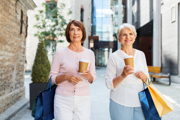 senior women with shopping bags and coffee in city - Foto, Imagen