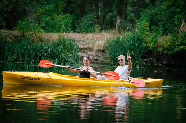A group of people kayaking on a calm river in the forest, the concept of outdoor activities, selective focus - Photo, image