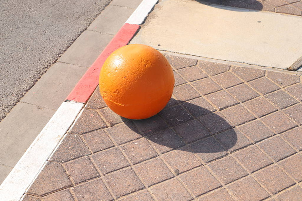 разноцветные бетонные шары лежат на тротуаре в городе и служат барьером от проезжей части
  - Фото, изображение