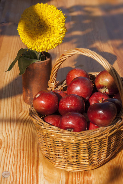 Red apples in wicker basket on wooden table background. Vitamin healthy food - Foto, afbeelding