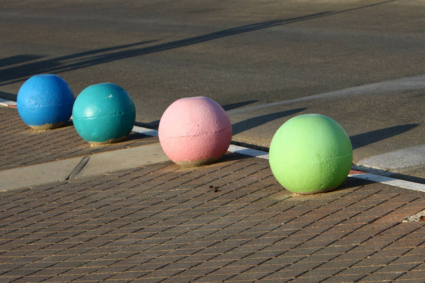 wielokolorowe betonowe kulki leżą na chodniku w mieście i służą jako bariera z jezdni  - Zdjęcie, obraz