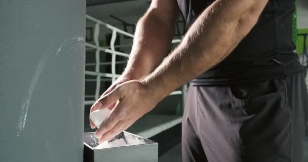 Sportowiec przygotowuje się, rozrywa ręce po magnezji w centrum fitness - Materiał filmowy, wideo